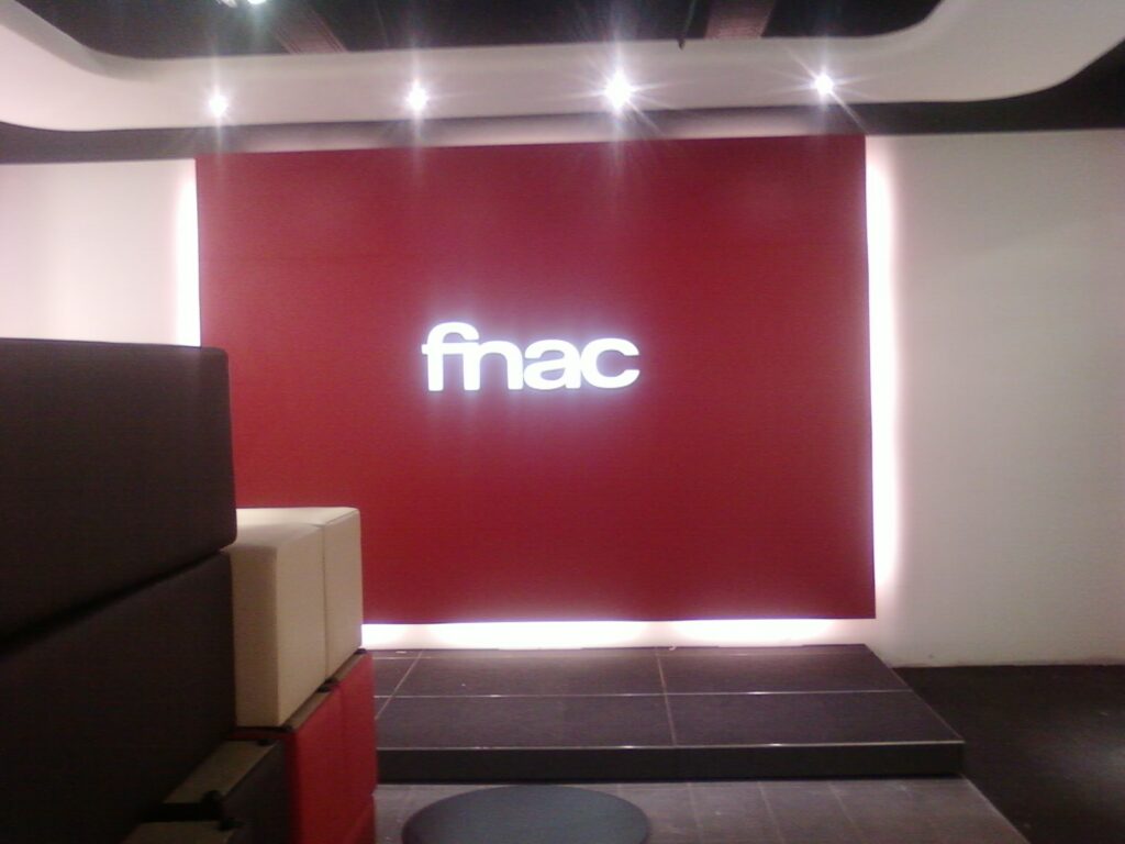 Acceso de FNAC con rótulo iluminado y luminarias en el techo