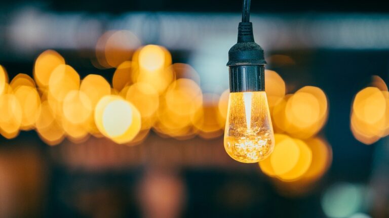 Bombilla de filamento encendida con luces cálidas al fondo